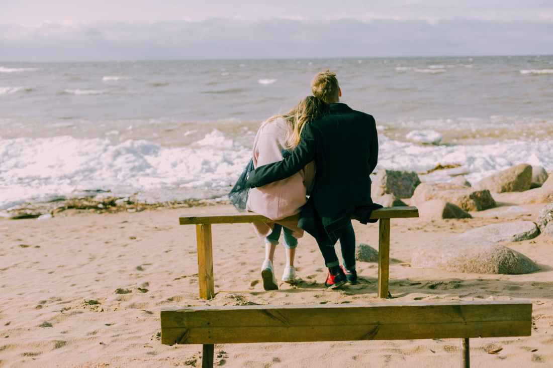 man and woman hugging and sitting on a bench